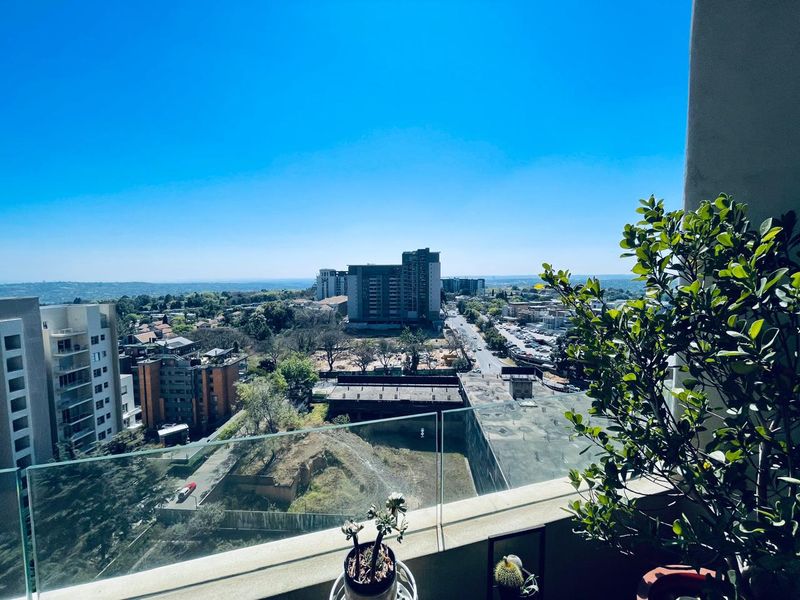 Elevated urban view from a balcony featuring a modern glass balustrade overlooking the surrounding cityscape.