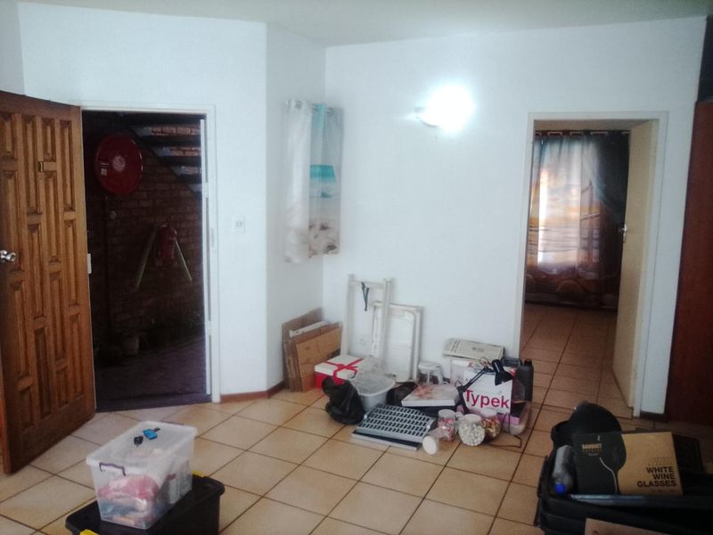 A tiled hallway area connecting multiple rooms, featuring a wooden door and neutral wall finishes.