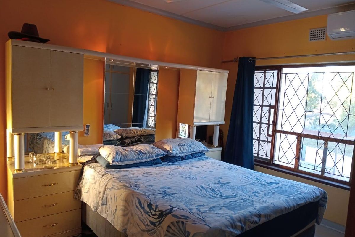 A bedroom featuring built-in cabinetry with integrated mirrors, a ceiling fan, and security bars on the window.