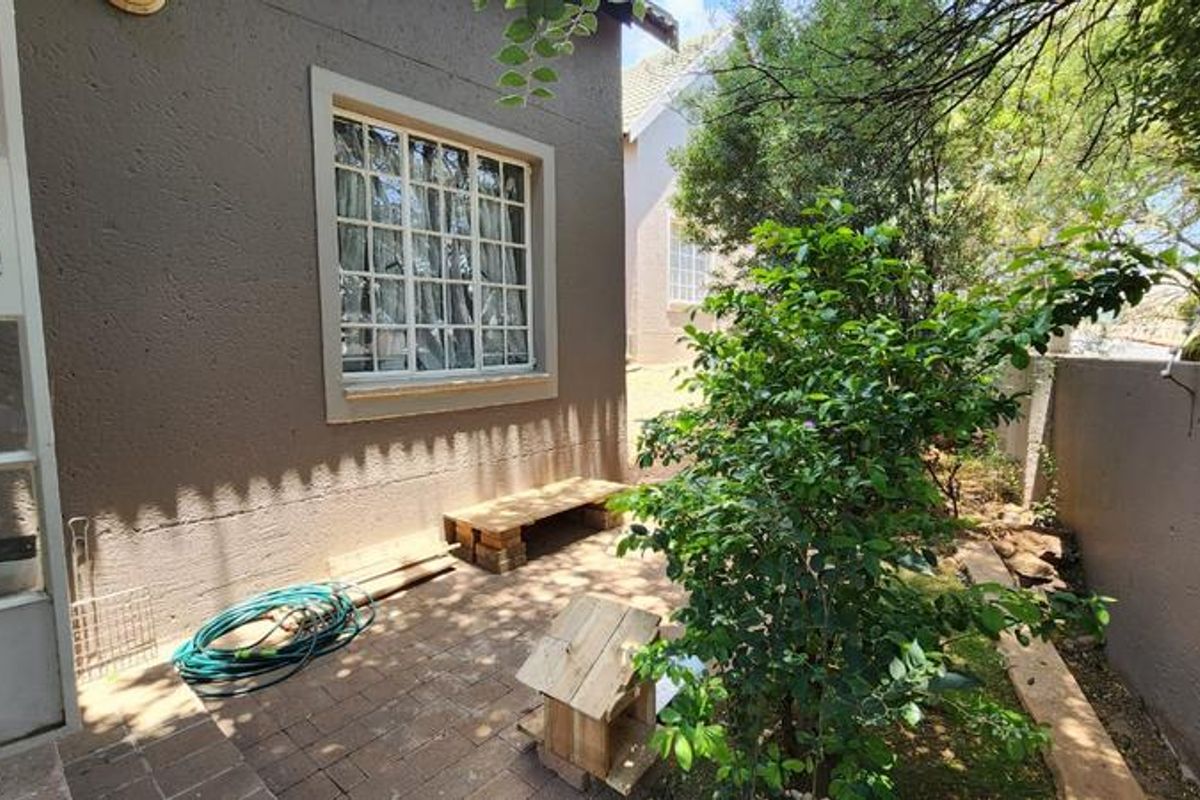 A private rear courtyard featuring paved flooring, a textured exterior wall, and established garden greenery, providing a quiet outdoor space.