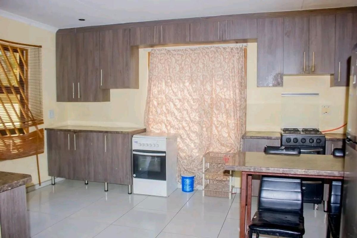 A functional kitchen featuring wood-look cabinetry, tiled flooring, and built-in stove and oven units.