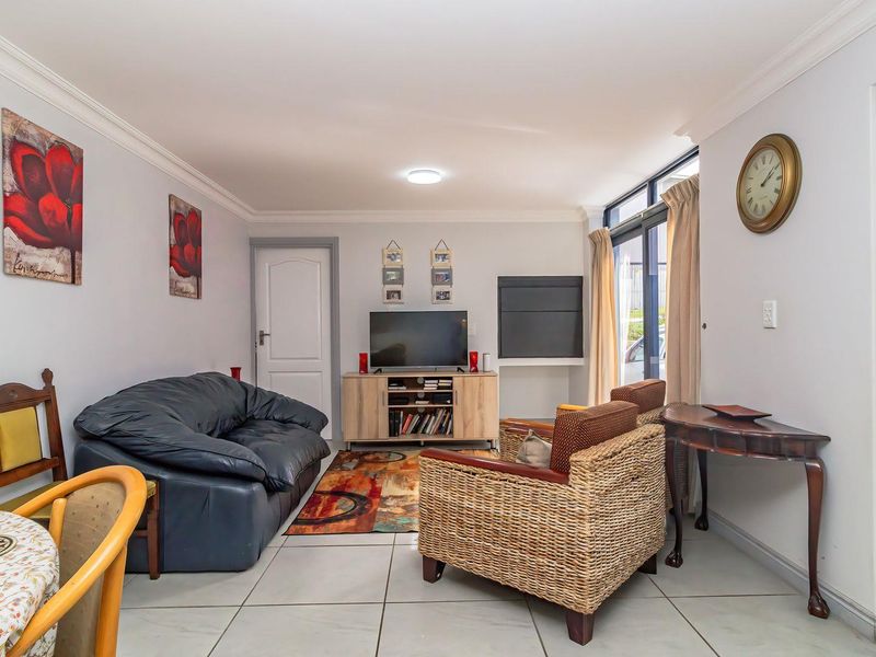A well-lit living room featuring neutral tiled flooring, coved ceiling details, and a sliding glass door providing access to the exterior.