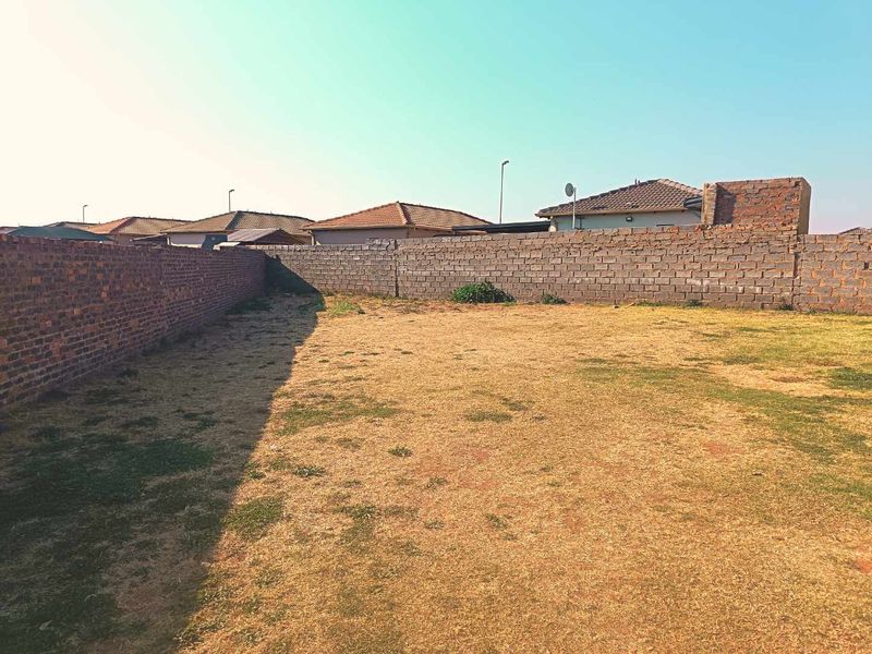 A spacious, undeveloped backyard area enclosed by perimeter brick walls, offering a blank canvas for landscaping or outdoor improvements.