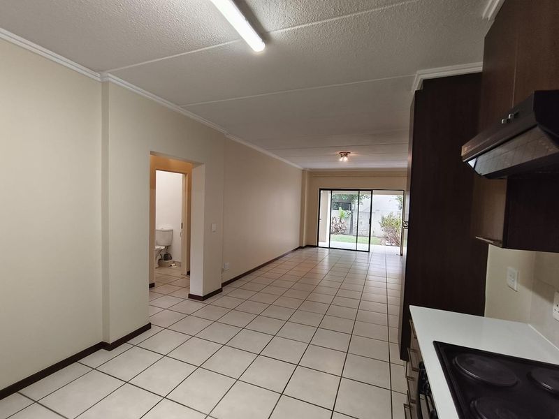 Spacious open-plan living area featuring tiled floors, a functional kitchen with built-in cabinetry, and direct access to an outdoor space via sliding doors.