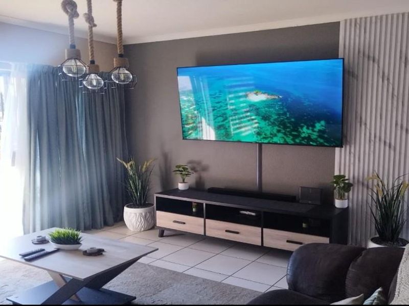 A modern living room featuring tiled flooring, decorative wall paneling, and a sliding glass door leading to an outdoor area.