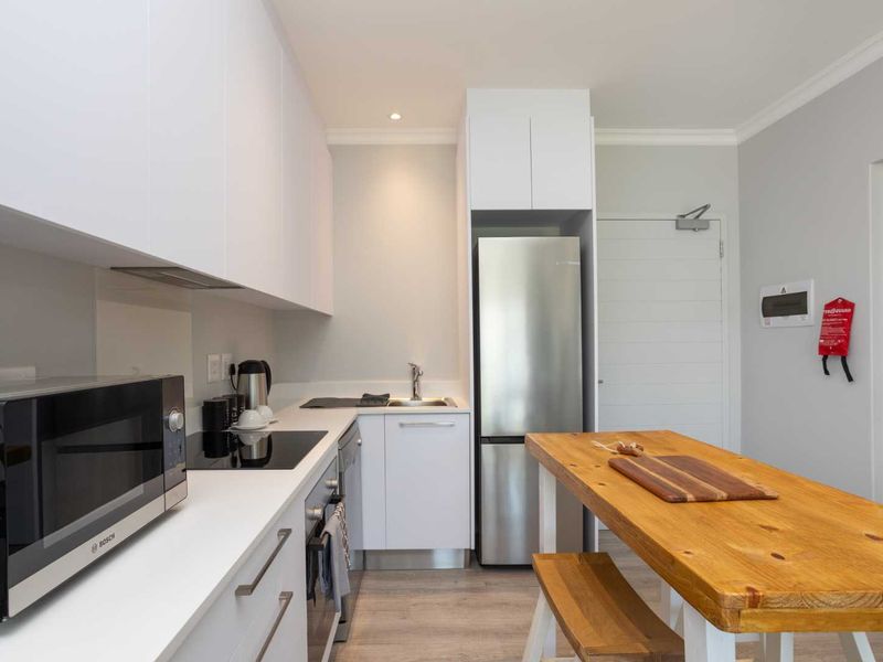 Modern kitchen featuring sleek white cabinetry, integrated appliances, electric hob, and high-quality finishes in a clean, contemporary design.