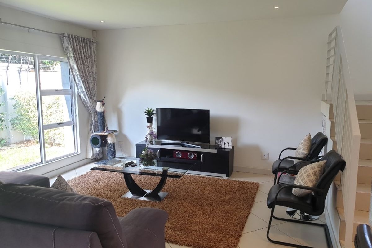 A bright living room featuring tiled flooring, recessed ceiling lighting, and large sliding glass doors providing access to the outdoor area.