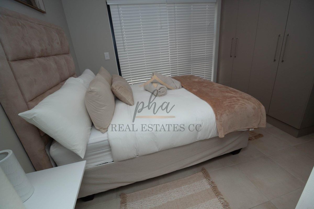 A well-maintained bedroom featuring neutral tones, built-in cupboards, and horizontal blinds, offering a clean and comfortable living space.