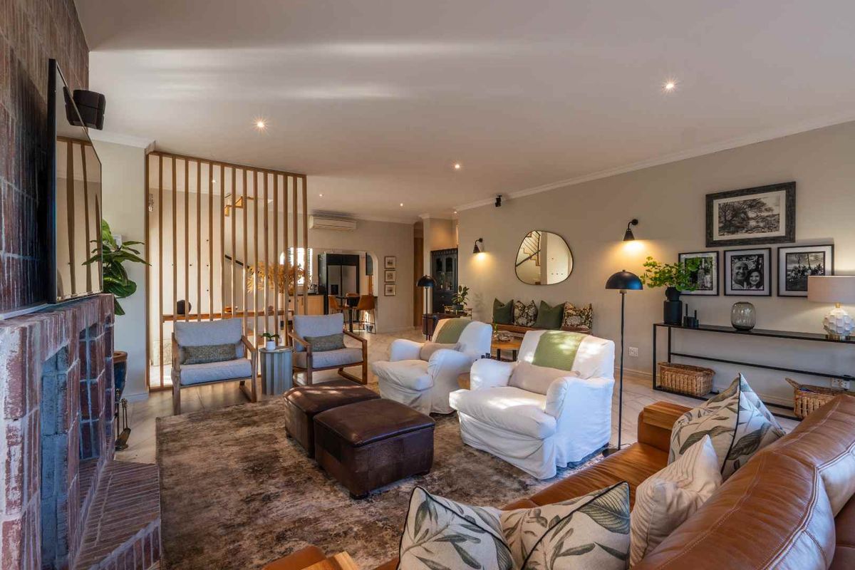 Spacious living room featuring a prominent brick fireplace, recessed lighting, and a decorative timber slat divider separating the space from the kitchen area.