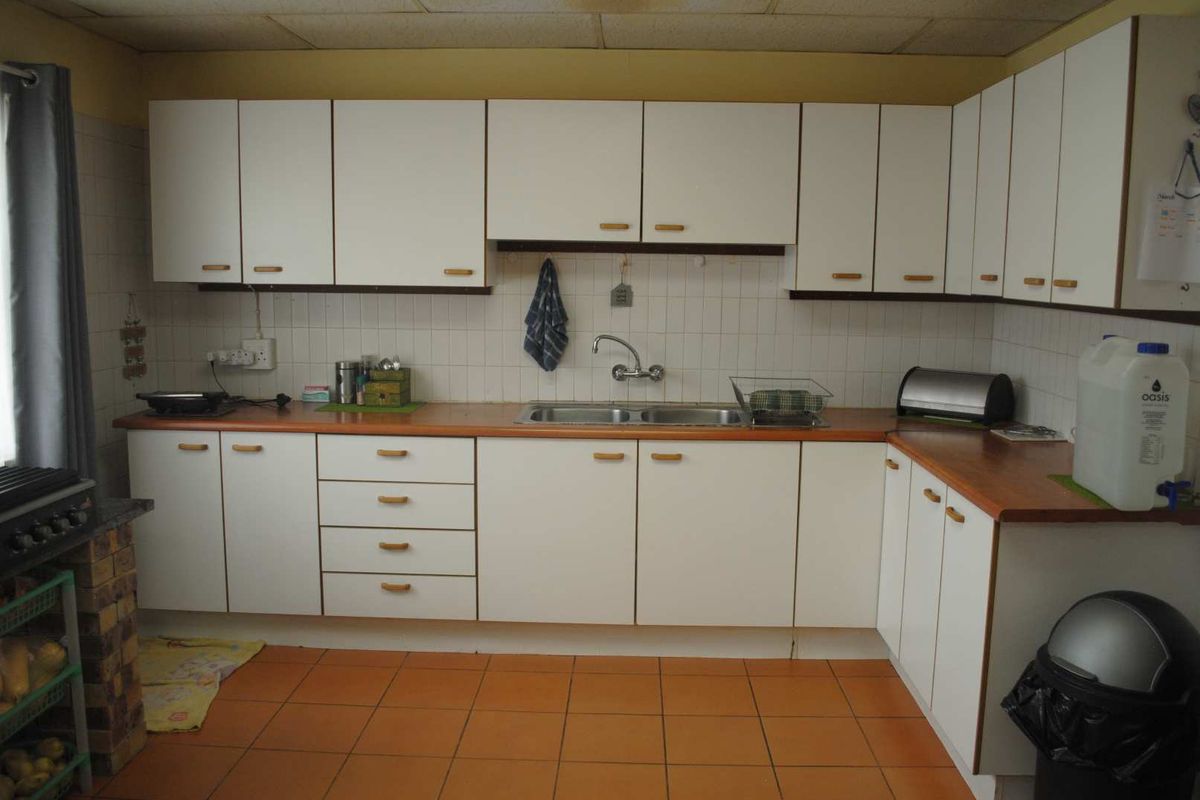 A functional kitchen featuring white cabinetry, laminate countertops, a double basin sink, and tiled flooring.