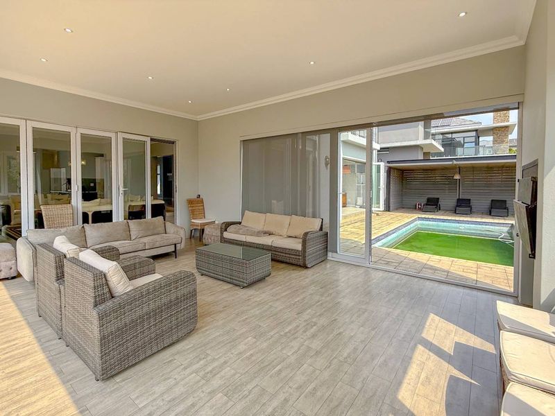 Spacious covered patio featuring tiled flooring, recessed lighting, and large sliding glass doors providing seamless access to the outdoor pool area.