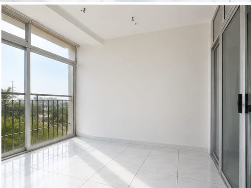A bright, empty balcony featuring tiled flooring, large sliding glass doors, and a metal balustrade with views.