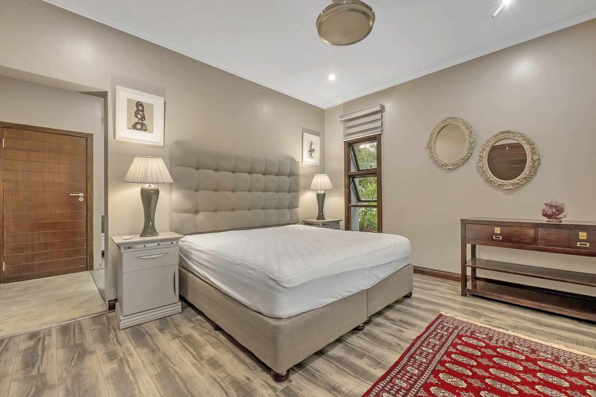 A well-maintained bedroom featuring laminate flooring, neutral wall tones, and a timber door, offering a comfortable and functional living space.