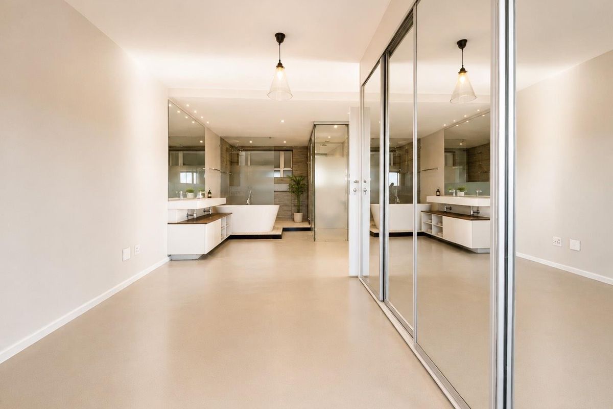 Spacious modern bathroom featuring a freestanding bathtub, walk-in shower, double vanity, and large mirrored sliding wardrobe doors in a clean, minimalist setting.