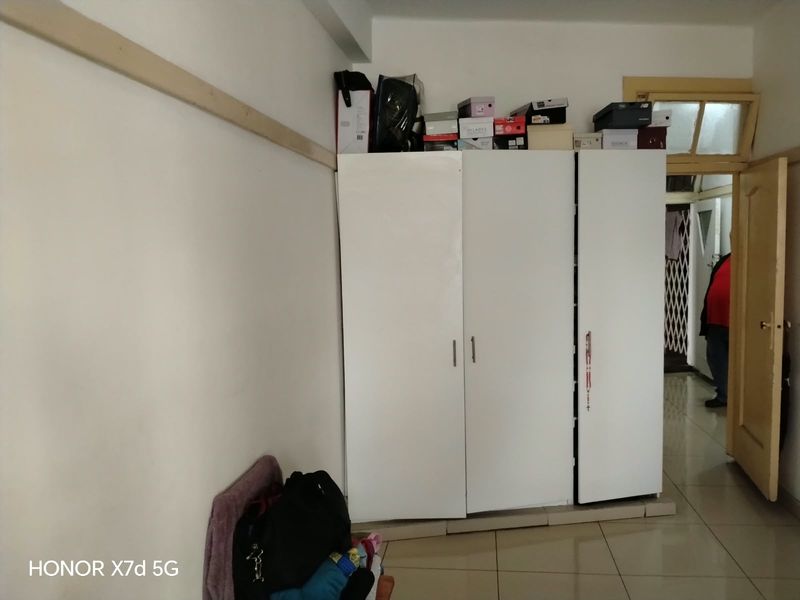 A bedroom featuring a white built-in wardrobe and tiled flooring, providing functional storage space within the apartment.