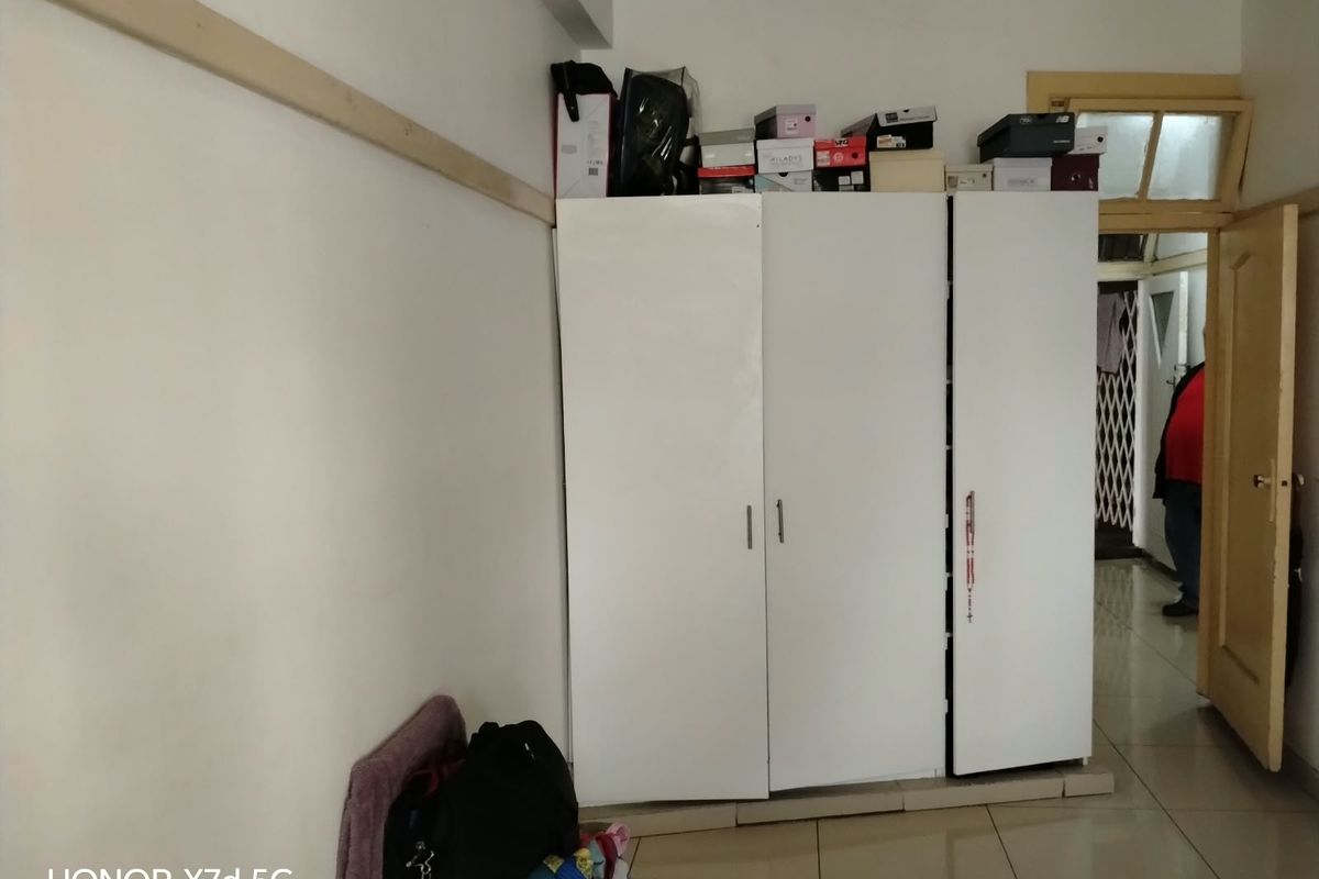 A bedroom featuring a white built-in wardrobe and tiled flooring, providing functional storage space within the apartment.