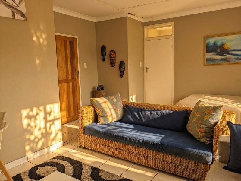 A living room area featuring tiled flooring and wooden doors, showing signs of wear on the ceiling and cornice requiring maintenance.