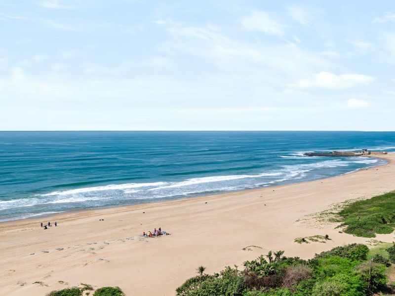 A scenic elevated view of the coastline, featuring a sandy beach and the ocean.
