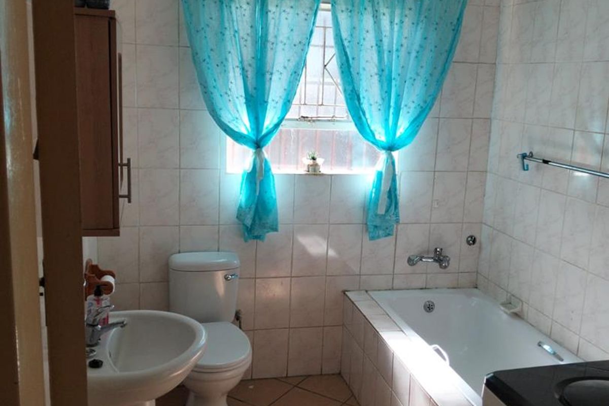 A functional bathroom featuring a pedestal basin, toilet, and a built-in bathtub with tiled finishes throughout.