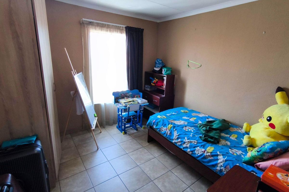 A functional bedroom featuring tiled flooring and a built-in wardrobe, providing a practical space with natural light.