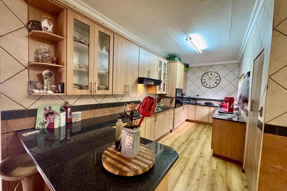 Spacious kitchen featuring light wood cabinetry, dark granite countertops, integrated appliances, and a functional layout with ample storage and workspace.