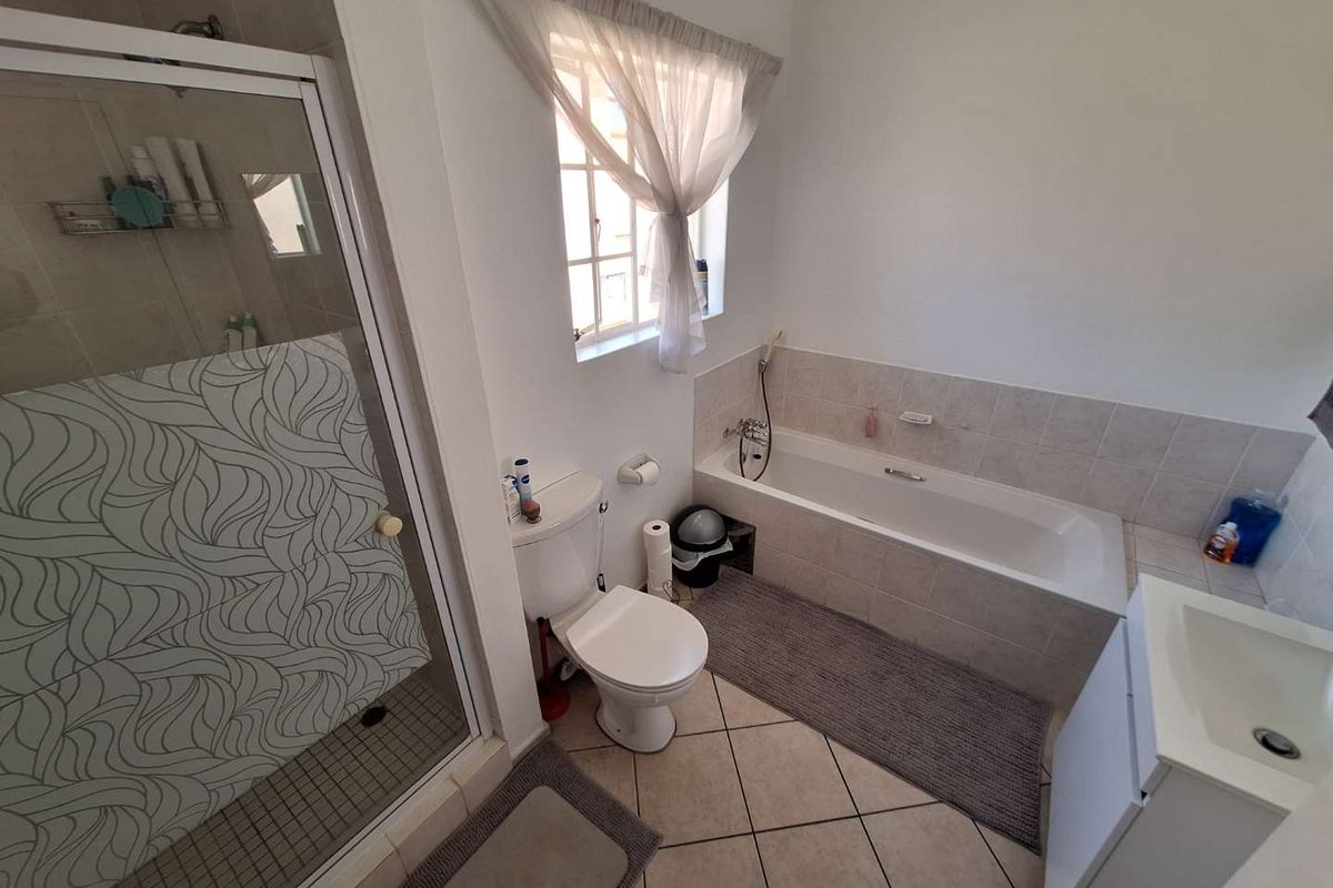 A functional bathroom featuring a tiled shower enclosure, a built-in bathtub with tiled surround, a toilet, and a vanity basin.