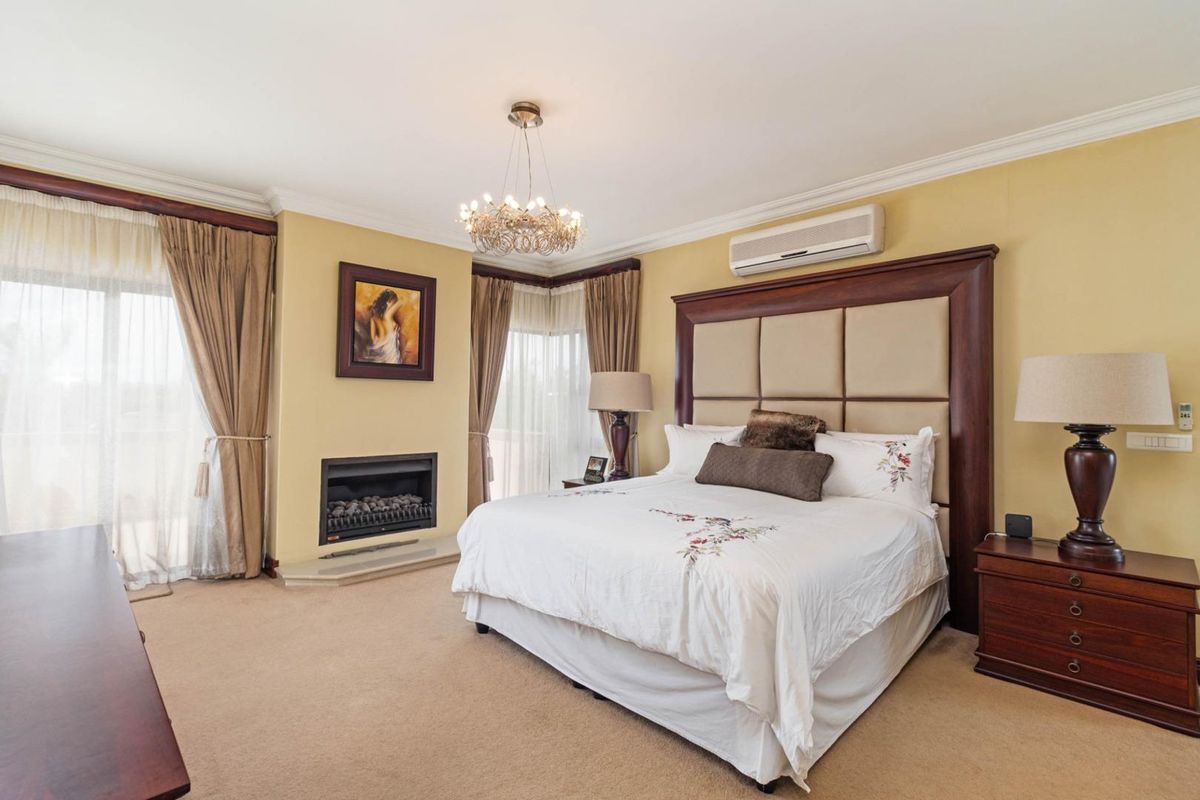 Spacious bedroom featuring a built-in fireplace, wall-mounted air conditioning unit, crown molding, and sliding glass doors leading to an outdoor area.