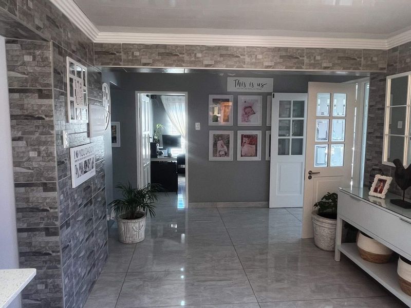 Welcoming entrance hall featuring polished tiled flooring, a decorative stone-cladding feature wall, and classic french doors leading to adjacent living spaces.