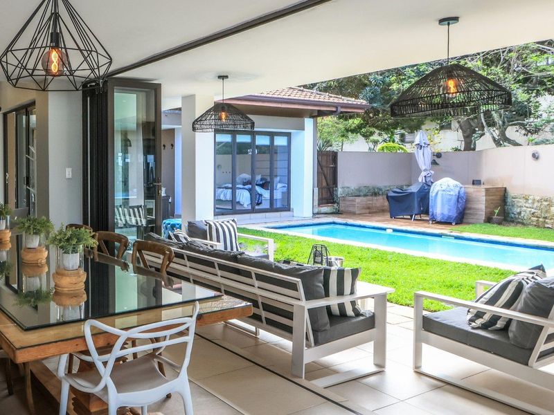 Spacious covered patio featuring tiled flooring and seamless flow to a private garden and swimming pool area, ideal for outdoor entertaining.