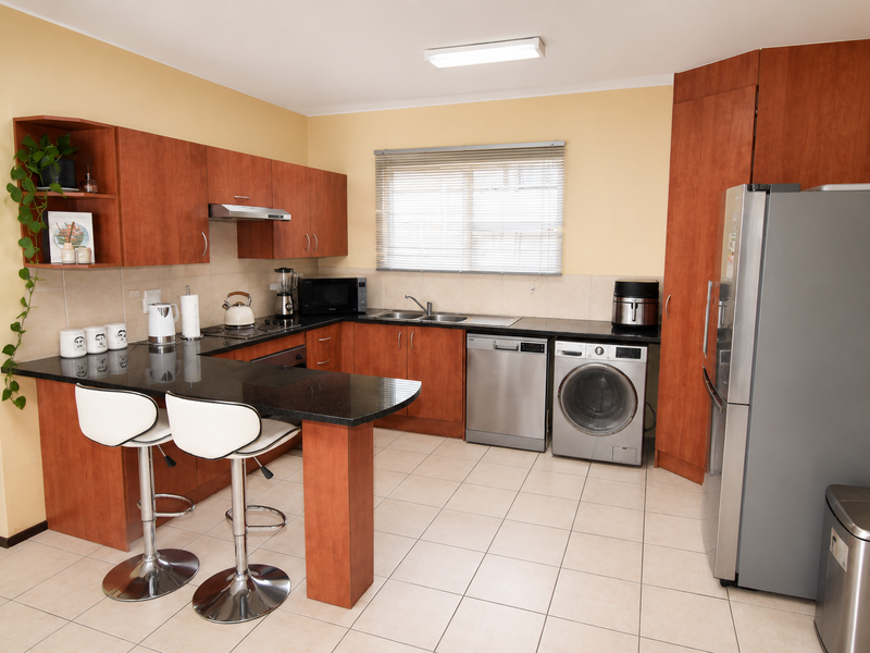 A functional kitchen featuring laminate cabinetry, granite countertops, a breakfast bar, and integrated space for laundry appliances.