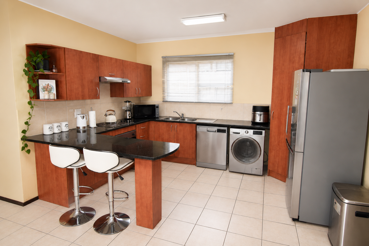 A functional kitchen featuring laminate cabinetry, granite countertops, a breakfast bar, and integrated space for laundry appliances.