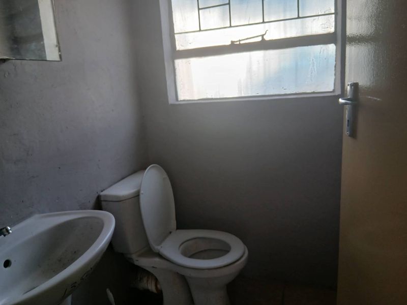 A compact bathroom featuring a pedestal basin and toilet, requiring cosmetic updates to improve the overall finish and appeal.