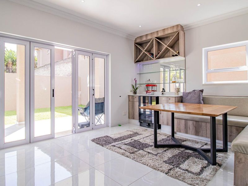 A bright living area featuring built-in bar cabinetry, integrated bench seating, and large sliding glass doors that open onto the garden.