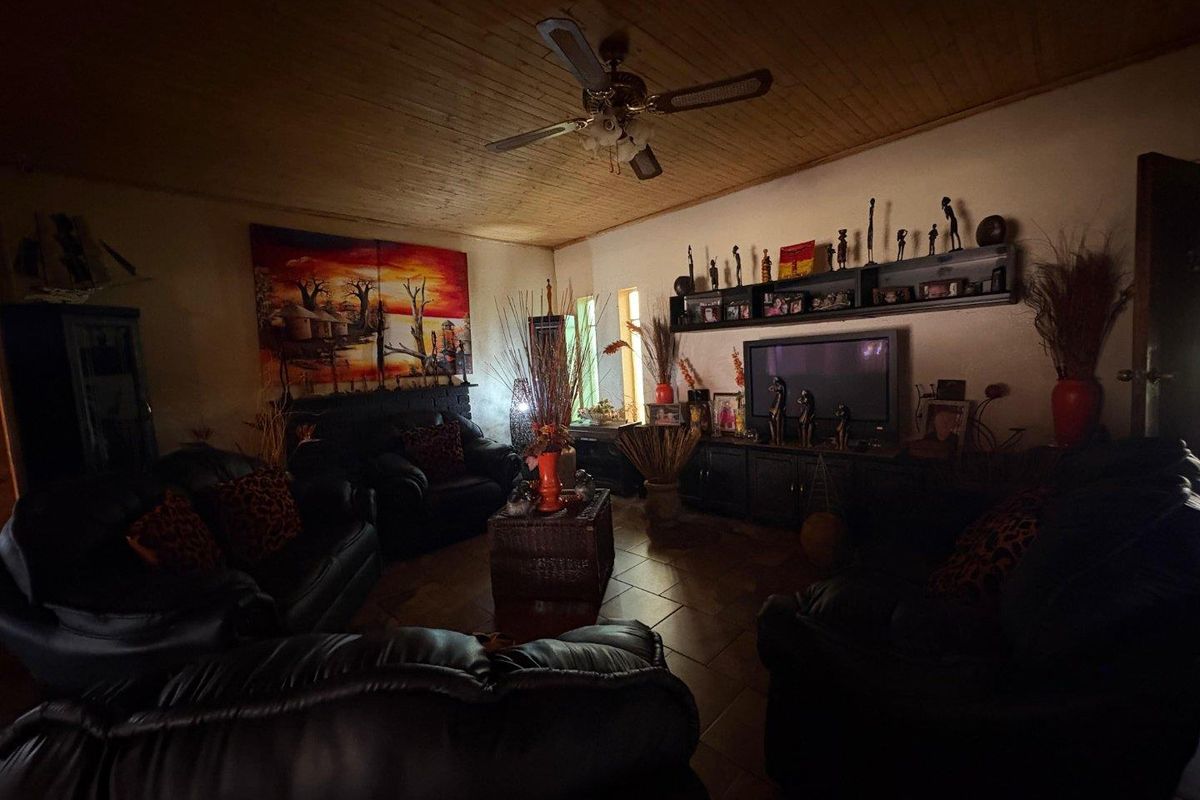 A cozy living room featuring a timber-clad ceiling, a ceiling fan, and tiled flooring, creating a warm and inviting atmosphere.