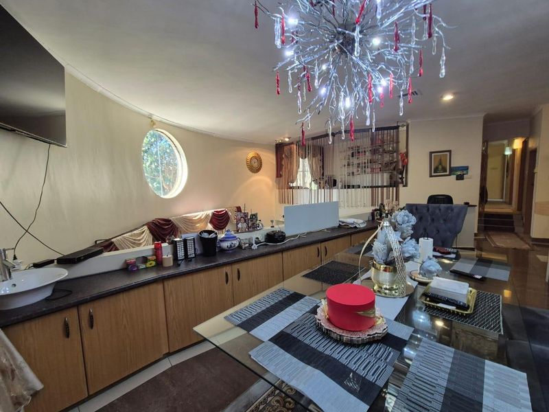 Open plan living and dining area featuring built-in cabinetry, a unique porthole window, and a decorative chandelier.