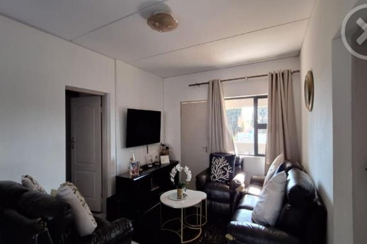 A compact living room featuring neutral walls, a ceiling light fixture, and access to adjacent rooms via internal doors.