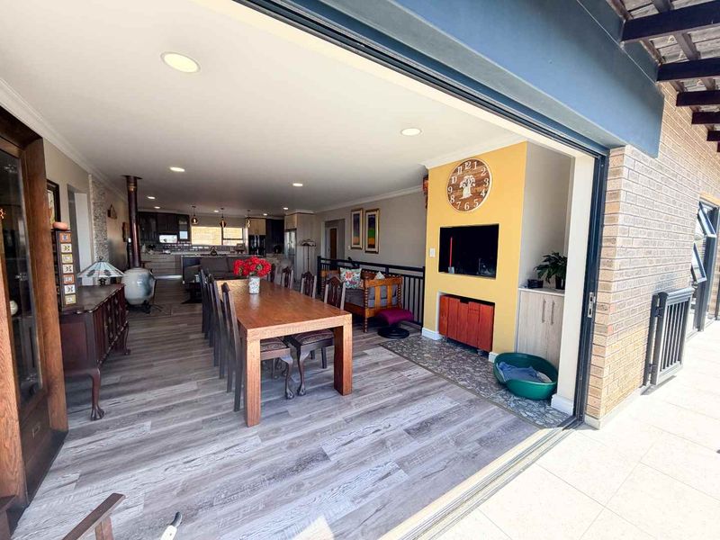 Spacious open-plan living and dining area featuring modern laminate flooring, recessed lighting, a wood-burning stove, and seamless flow to the outdoor patio.