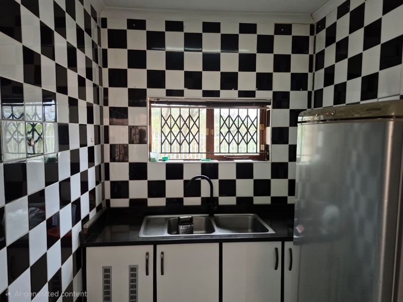 A compact kitchen featuring high-contrast black and white checkered wall tiles, a double basin sink with a modern black faucet, and dark granite countertops.