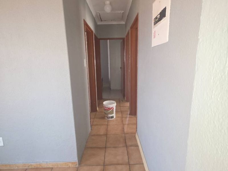 A functional hallway featuring tiled flooring and access to multiple internal rooms, providing a clean and neutral transition space.