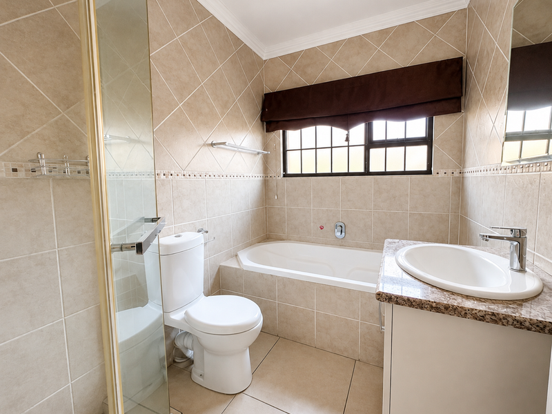 A clean, functional bathroom featuring a built-in bathtub, separate glass shower enclosure, and a vanity unit with a ceramic basin.