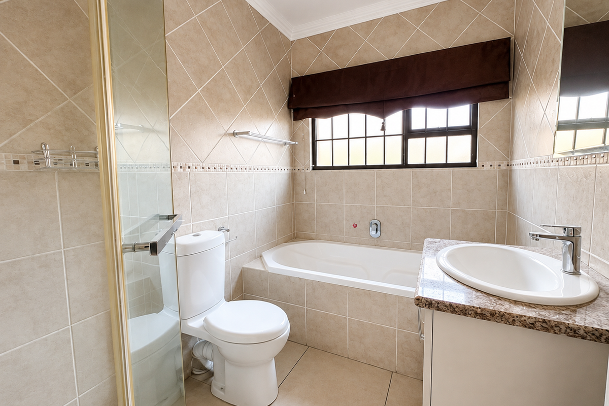 A clean, functional bathroom featuring a built-in bathtub, separate glass shower enclosure, and a vanity unit with a ceramic basin.