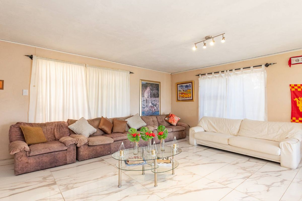 Spacious living room featuring large format marble-look floor tiles and modern track lighting, offering a bright and open atmosphere.
