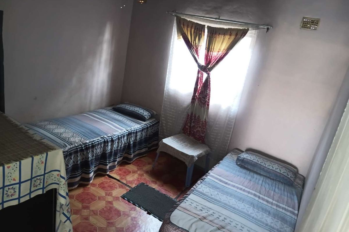 A compact bedroom featuring tiled flooring and a single window, requiring cosmetic updates to improve the overall finish and appeal.