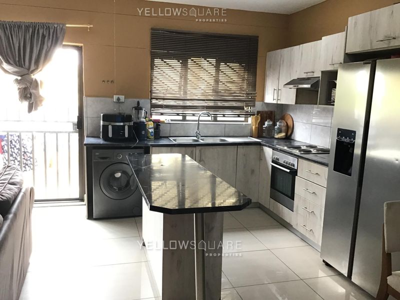 Functional kitchen featuring light wood-look cabinetry, dark countertops, built-in oven and hob, tiled flooring, and direct access to an outdoor area.