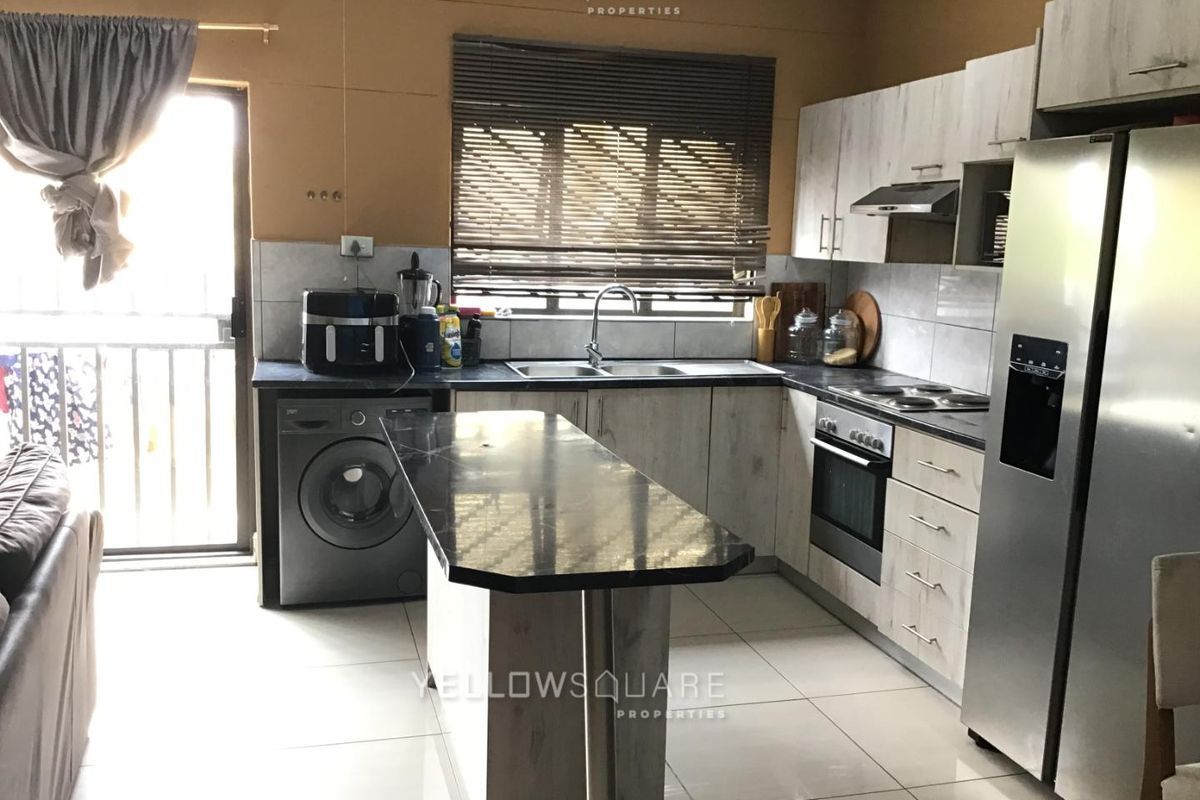 Functional kitchen featuring light wood-look cabinetry, dark countertops, built-in oven and hob, tiled flooring, and direct access to an outdoor area.