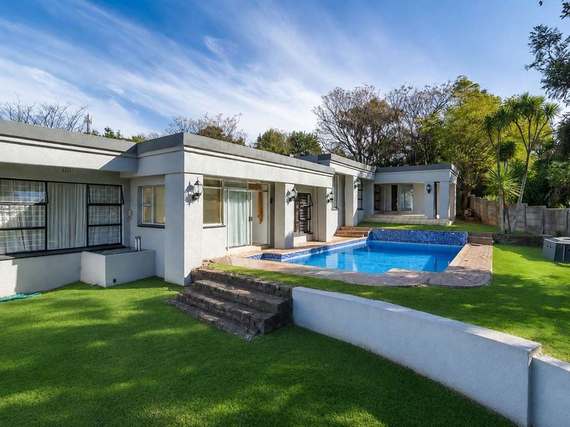 Rear view of the property featuring a swimming pool, landscaped lawn, brick steps, and direct access to the home via sliding glass doors.