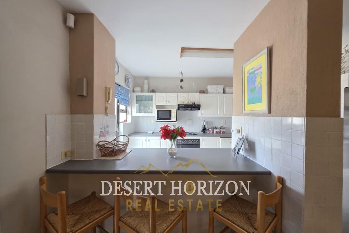 A functional kitchen featuring a breakfast bar, white cabinetry, built-in oven, and hob, providing a practical layout for daily meal preparation.