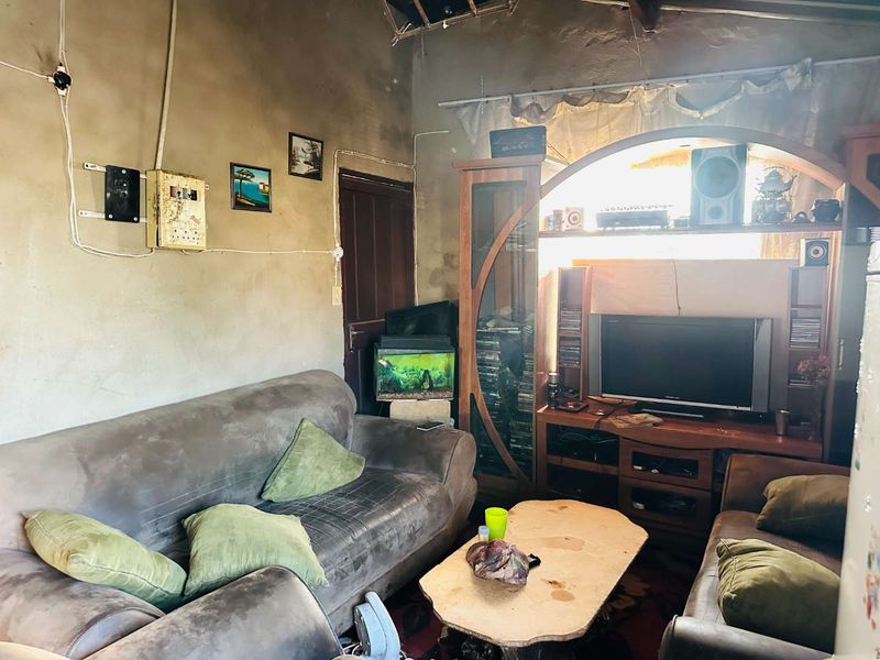 A living room space featuring unfinished wall surfaces, exposed electrical wiring, and a built-in arched wall niche.