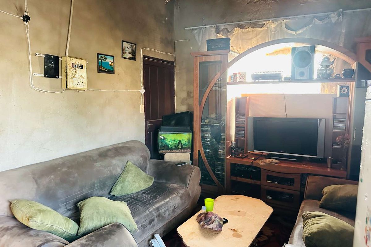 A living room space featuring unfinished wall surfaces, exposed electrical wiring, and a built-in arched wall niche.