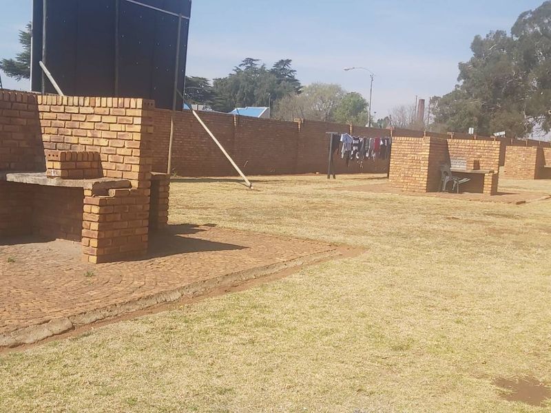A communal outdoor garden area featuring multiple built-in brick braai stations and a surrounding brick perimeter wall.